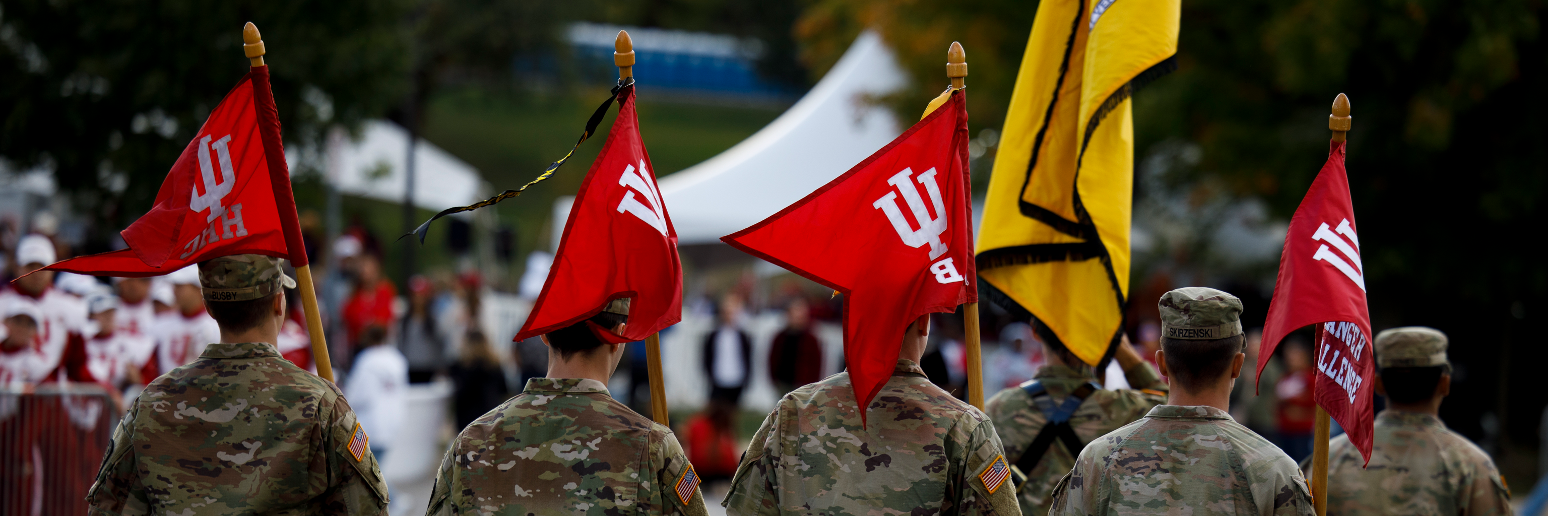 A group of soldiers marching while holding IU flags.